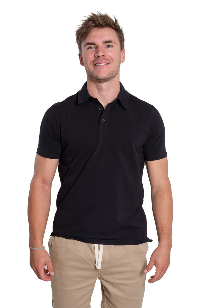 Man wearing black short-sleeve polo shirt with collar and button front, styled with beige pants.