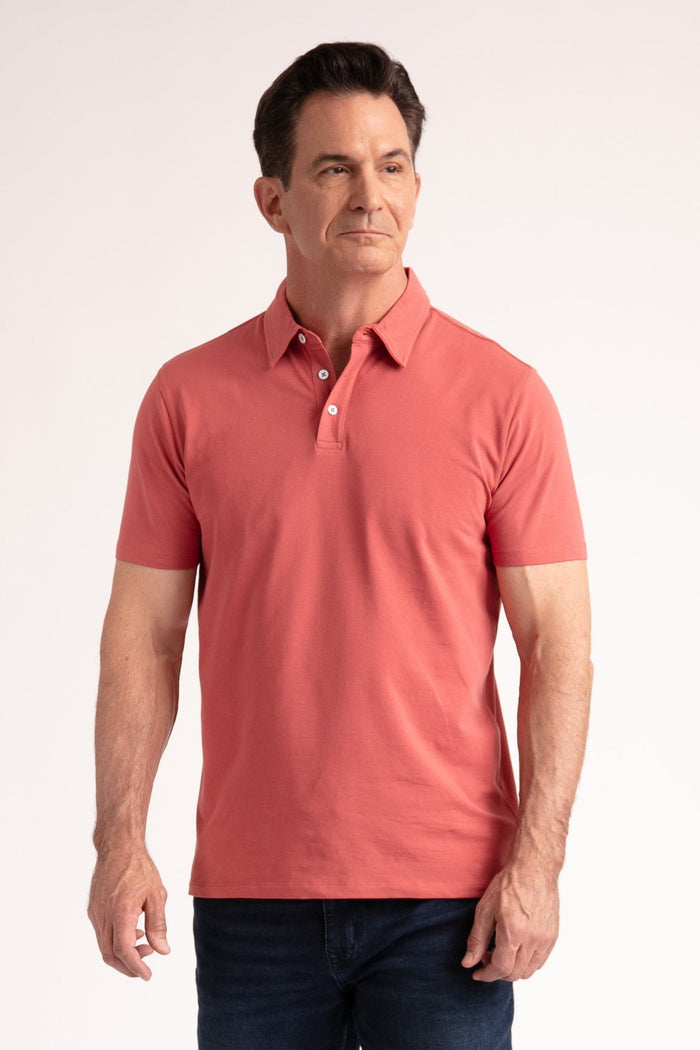 Man wearing coral-pink short-sleeve polo shirt with button placket and navy jeans.