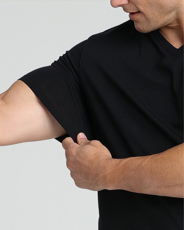 Man wearing black v-neck t-shirt with short sleeves, shown from shoulder to waist.