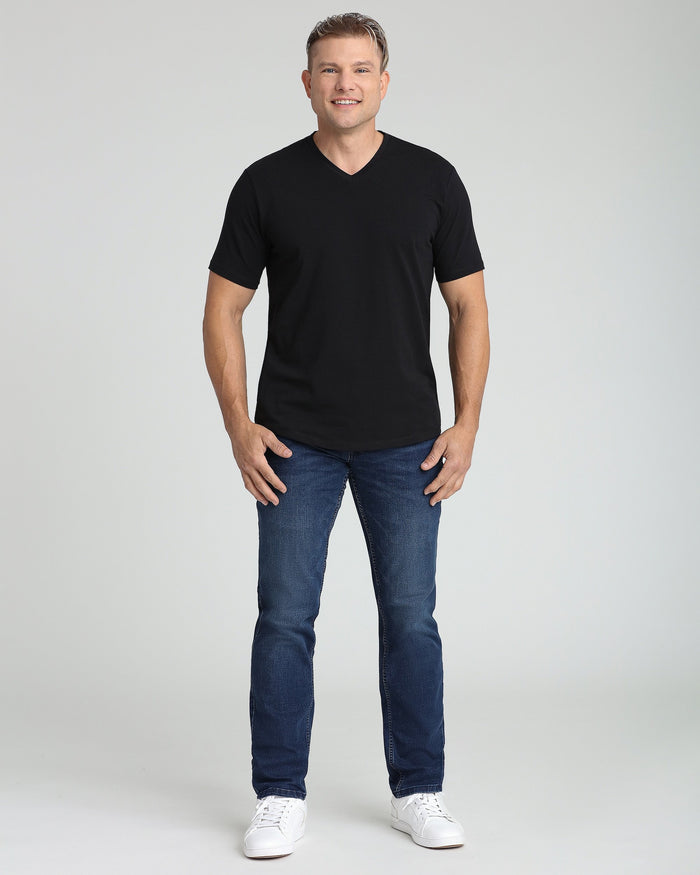 Man wearing black V-neck short-sleeve t-shirt with blue jeans and white sneakers.