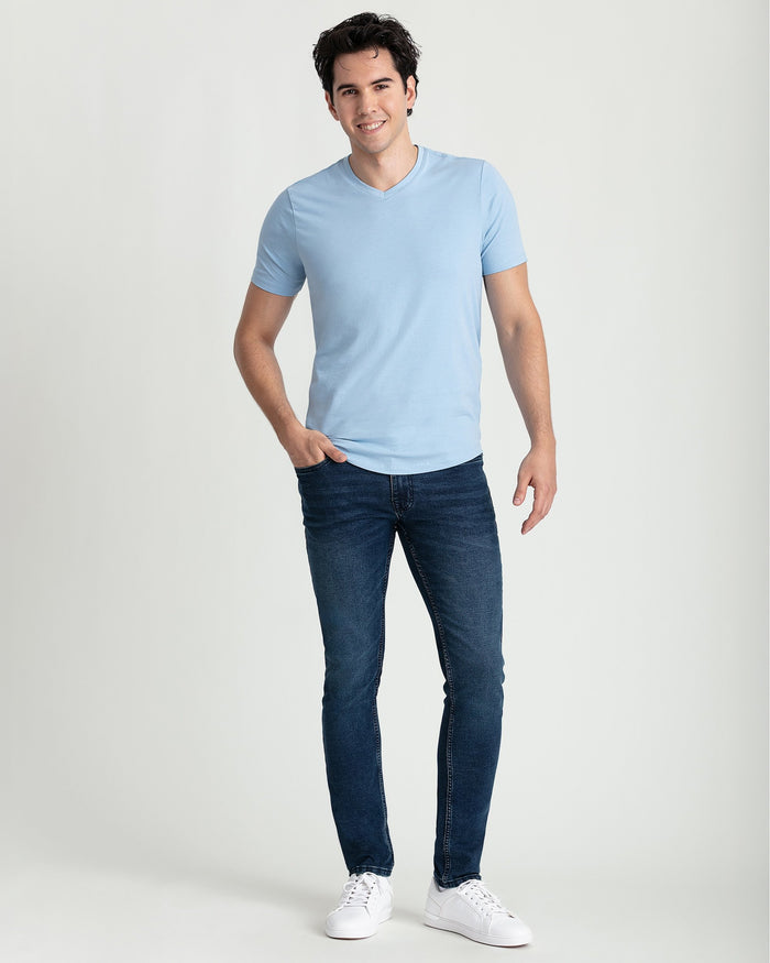 Man wearing light blue v-neck t-shirt with short sleeves and dark blue jeans.