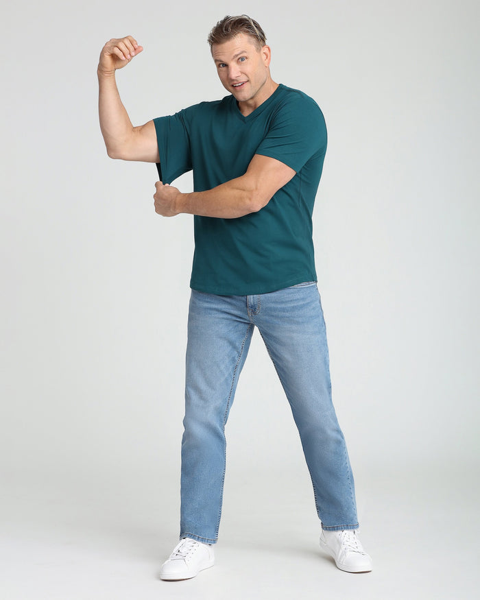 Man wearing teal v-neck t-shirt with short sleeves, paired with light blue jeans and white sneakers.