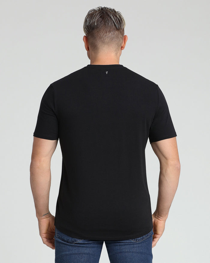 Man wearing black v-neck t-shirt and blue jeans, shown from back view.