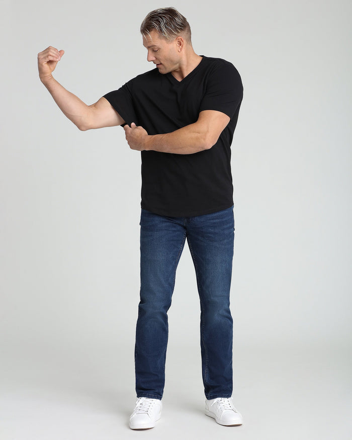 Man wearing black v-neck short-sleeve t-shirt with blue jeans and white sneakers.