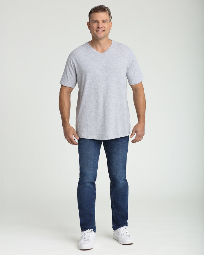 Man wearing heather grey v-neck t-shirt with short sleeves paired with dark jeans and white sneakers.