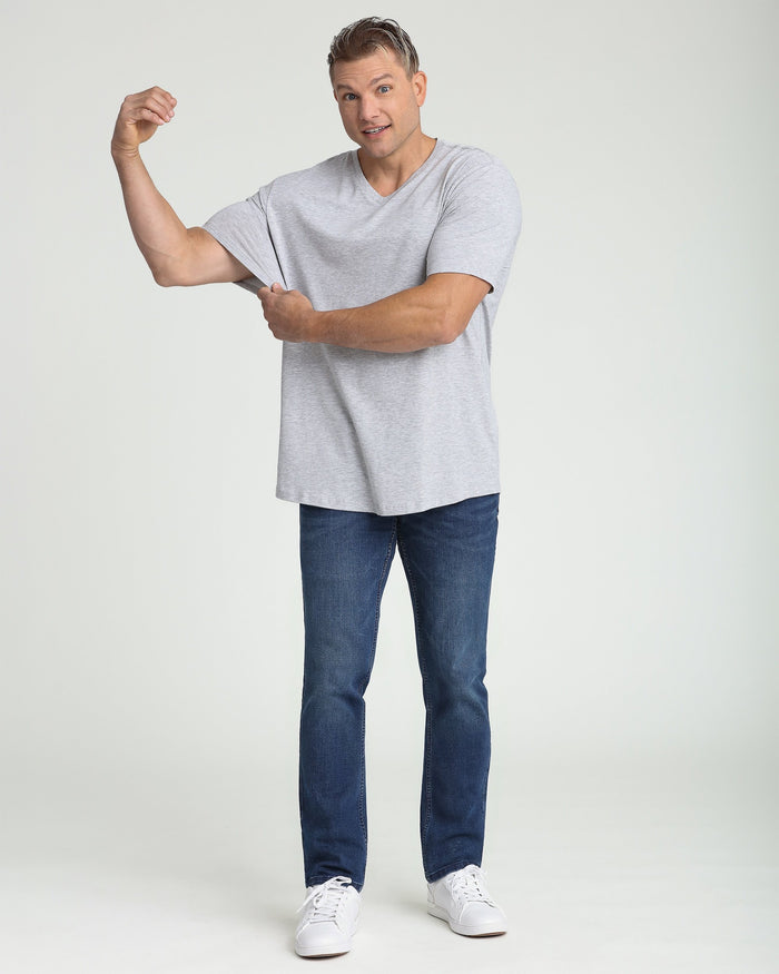 Man wearing heather grey v-neck t-shirt with short sleeves and dark blue jeans.