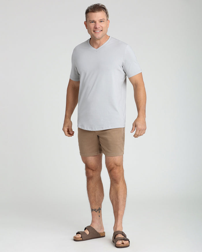 Man wearing light grey V-neck t-shirt with tan shorts and sandals.