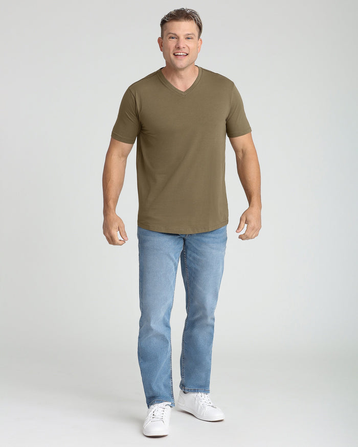 Man wearing military olive v-neck t-shirt and light blue jeans.