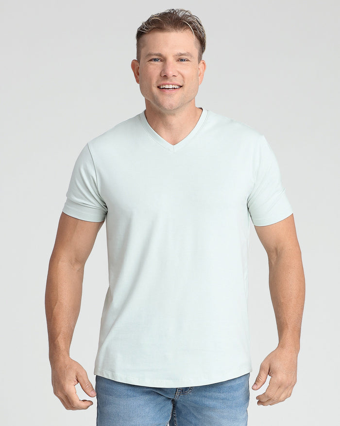 Man wearing mint green v-neck t-shirt with short sleeves paired with blue jeans.