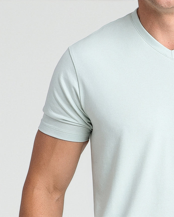 Mint green v-neck t-shirt with short sleeves on male model against neutral background.