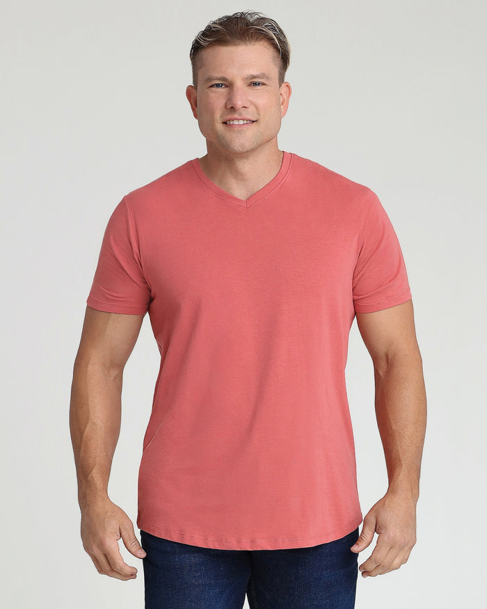 Man wearing a nantucket red v-neck t-shirt with short sleeves and dark jeans.