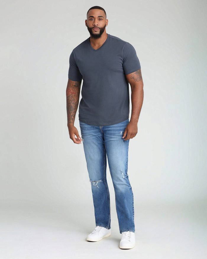 Man wearing steel gray v-neck short-sleeve t-shirt with blue jeans and white sneakers.