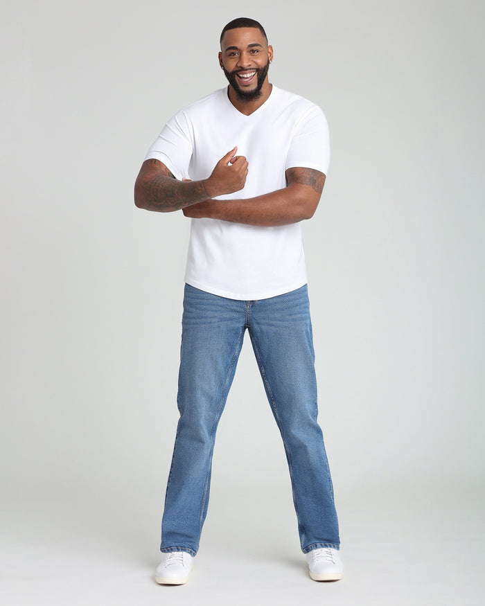 Man wearing white v-neck t-shirt with short sleeves and blue jeans.