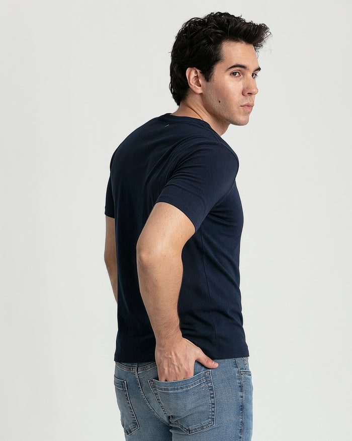 Man wearing navy V-neck t-shirt with short sleeves, shown from side angle with light background.