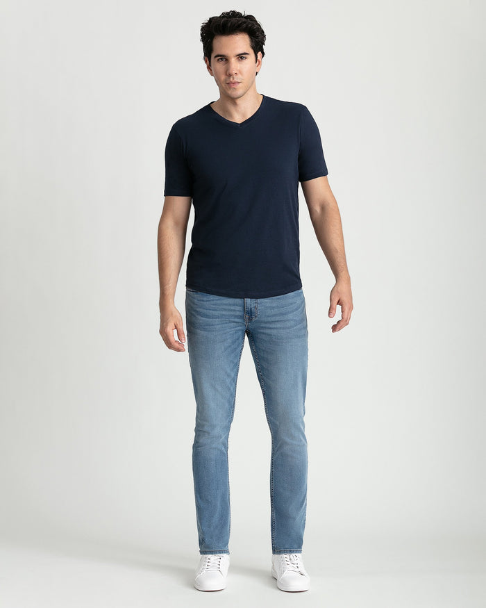 Man wearing navy short-sleeve V-neck t-shirt with light blue jeans and white sneakers.