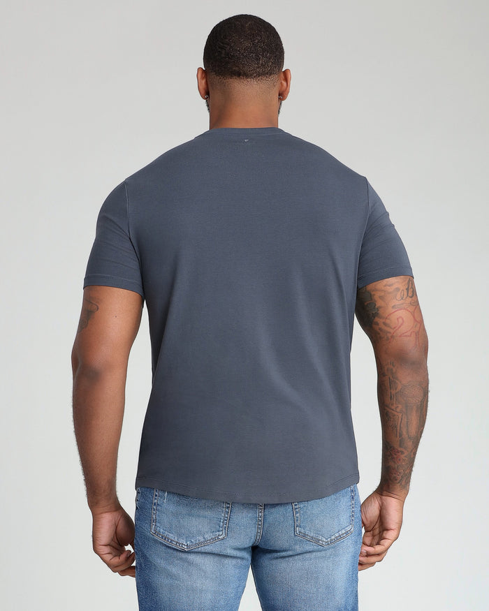 Steel gray v-neck t-shirt shown on model from back view, paired with light blue jeans.