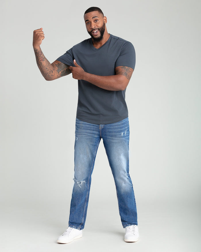 Steel gray V-neck t-shirt with short sleeves on a man wearing distressed blue jeans and white sneakers.