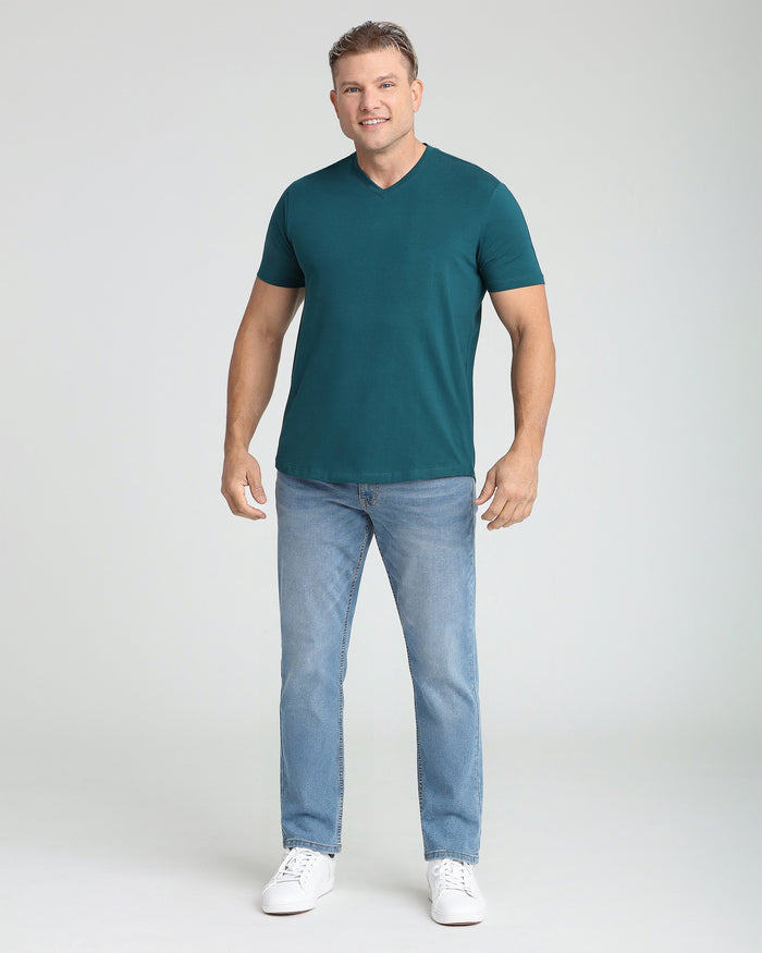 Teal V-neck short-sleeve t-shirt on male model wearing light blue jeans and white sneakers.