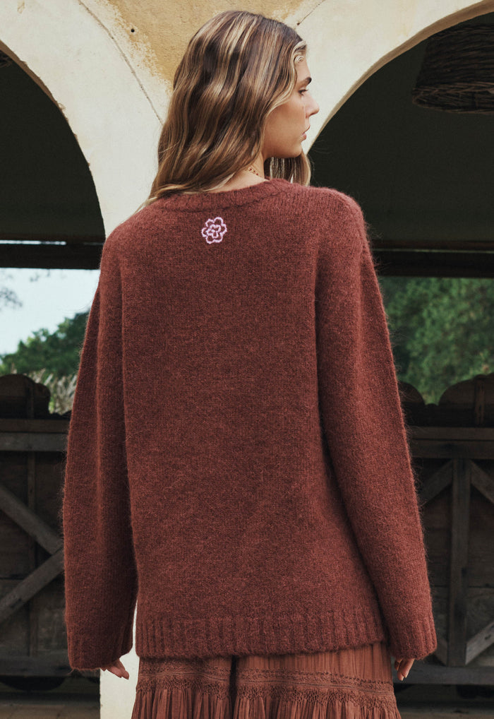Back view of a model wearing cocoa alpaca-wool sweater, showing floral embroidery detail at upper back