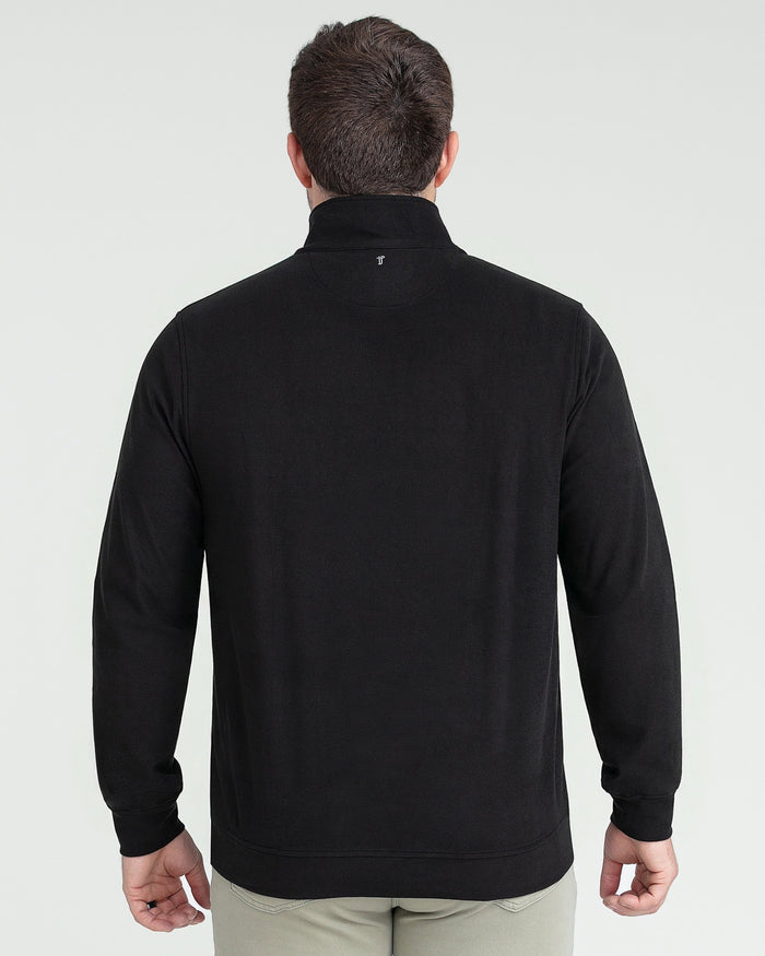 Black quarter zip pullover shown from back view on model wearing khaki pants.