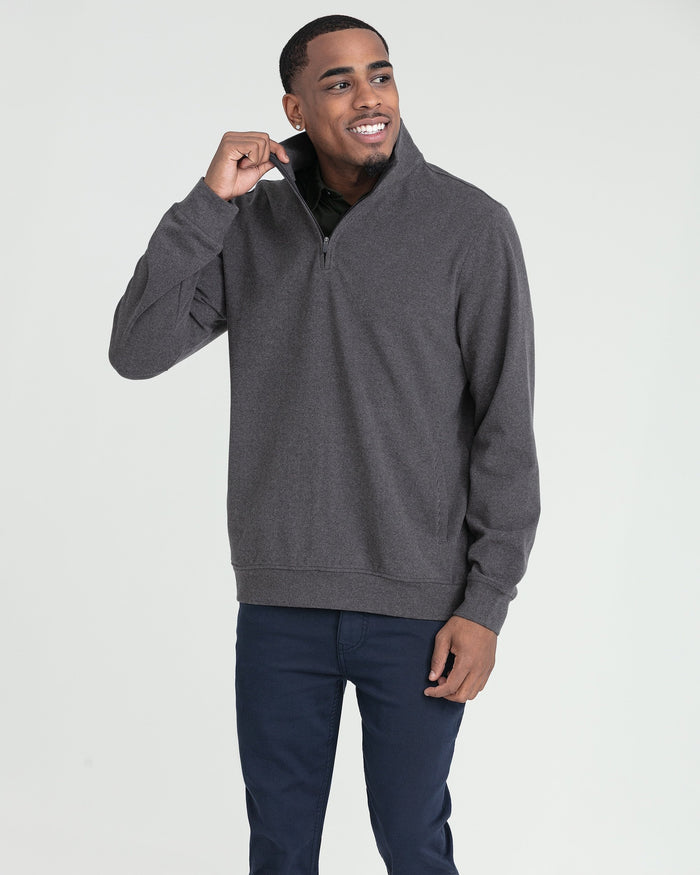 Man wearing charcoal heather quarter zip pullover with navy pants.