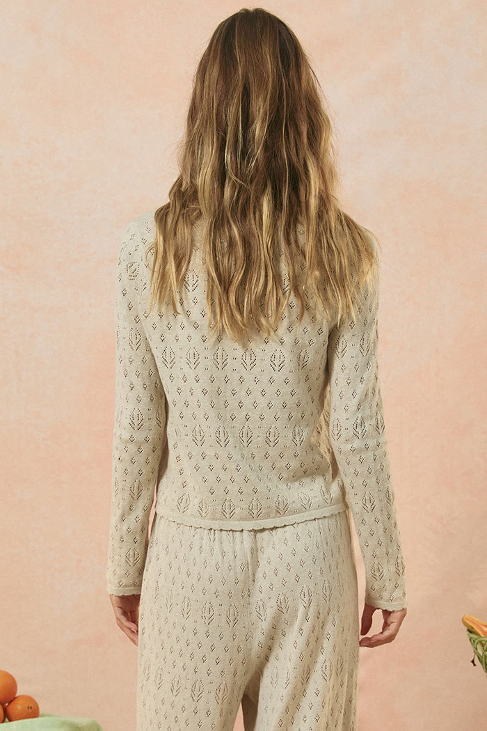 Back view of Rhodes Knit Cardigan in Sand showing pointelle knit pattern and scallop edge hem detail