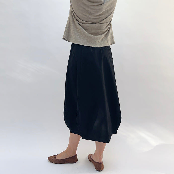 Rib Yoke Skirt in Black, back view showing bubble hem silhouette paired with a grey cardigan and brown flats