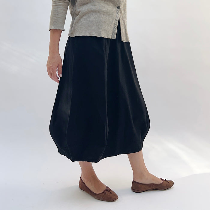 Rib Yoke Skirt in Black, three-quarter front view, paired with a beige button-front cardigan and brown ballet flats