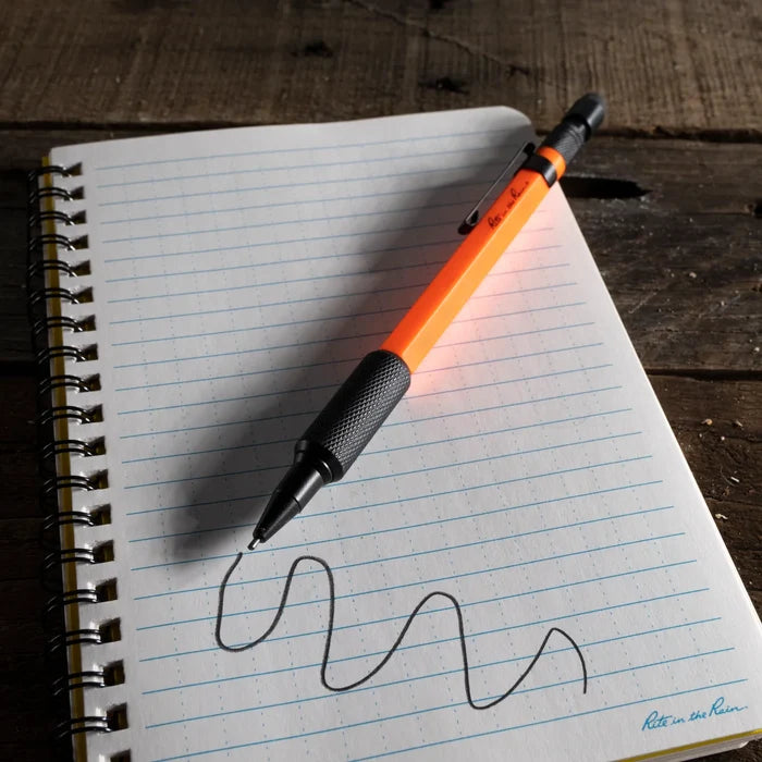 Orange pen with black cap on a notebook page with wavy line