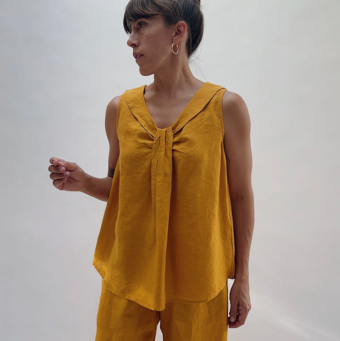 Front view of the Sailor Tank in Turmeric by Yuvita, showing the V-neckline with gathered twist detail, sailor collar, and relaxed linen silhouette in golden turmeric yellow, styled with matching linen wide-leg pants