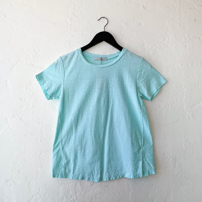 Light blue t-shirt on a black hanger against a white wall