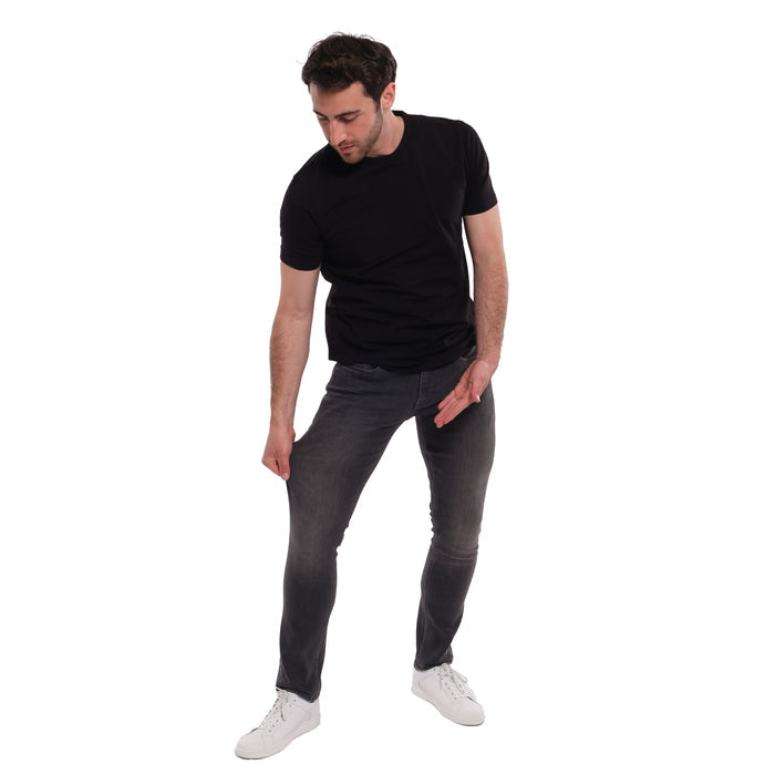 Man wearing black short-sleeve t-shirt and grey skinny fit jeans with white sneakers.