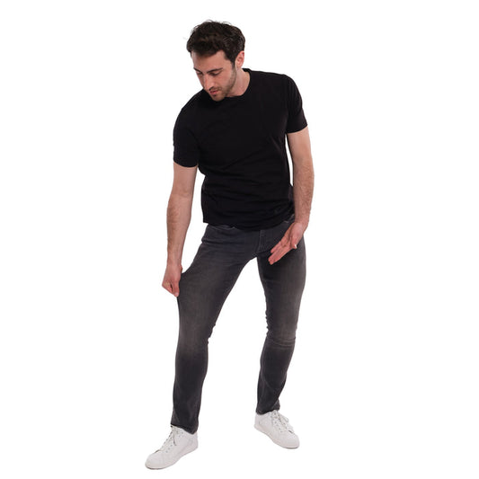 Man wearing black short-sleeve t-shirt and grey skinny fit jeans with white sneakers.