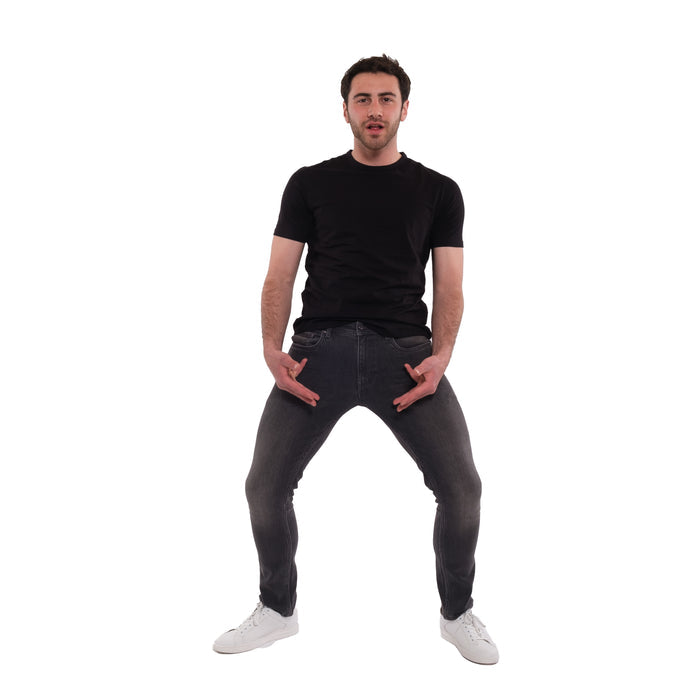 Man wearing black t-shirt and grey skinny fit jeans with white sneakers.