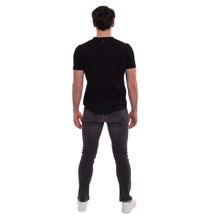 Man wearing black short-sleeve t-shirt and grey skinny fit jeans, shown from behind.