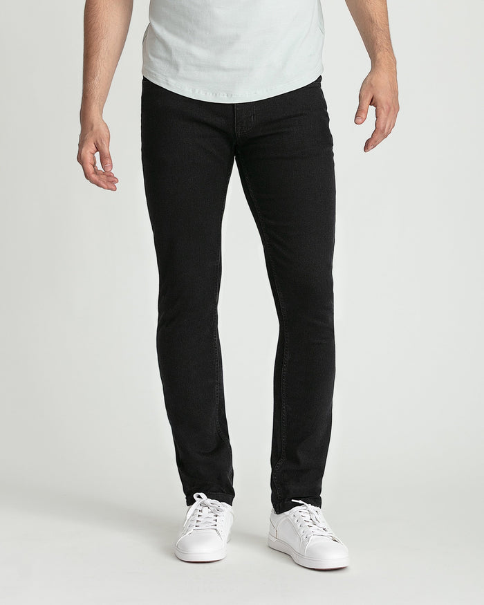 Man wearing white t-shirt and black skinny fit jeans with white sneakers.