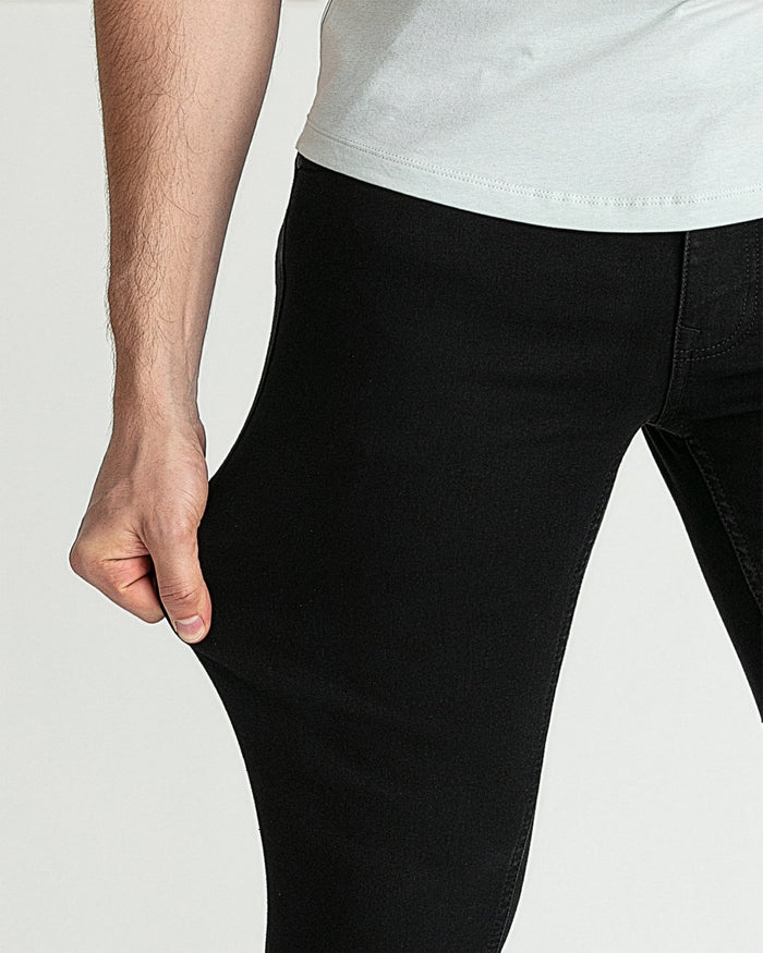Man wearing black skinny fit jeans with white t-shirt, shown from waist down.