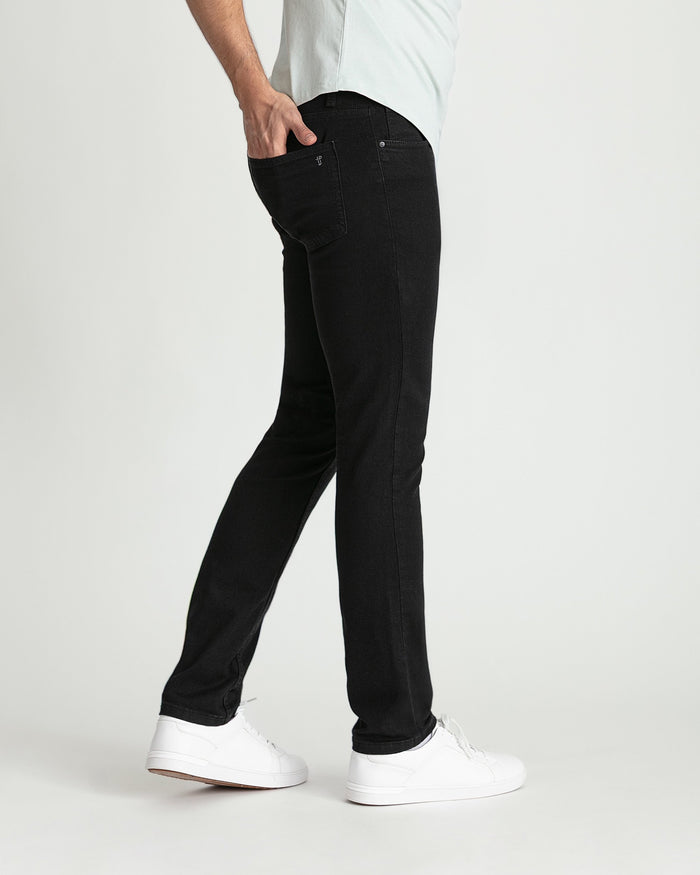 Man wearing black skinny fit jeans with white sneakers and light gray shirt.