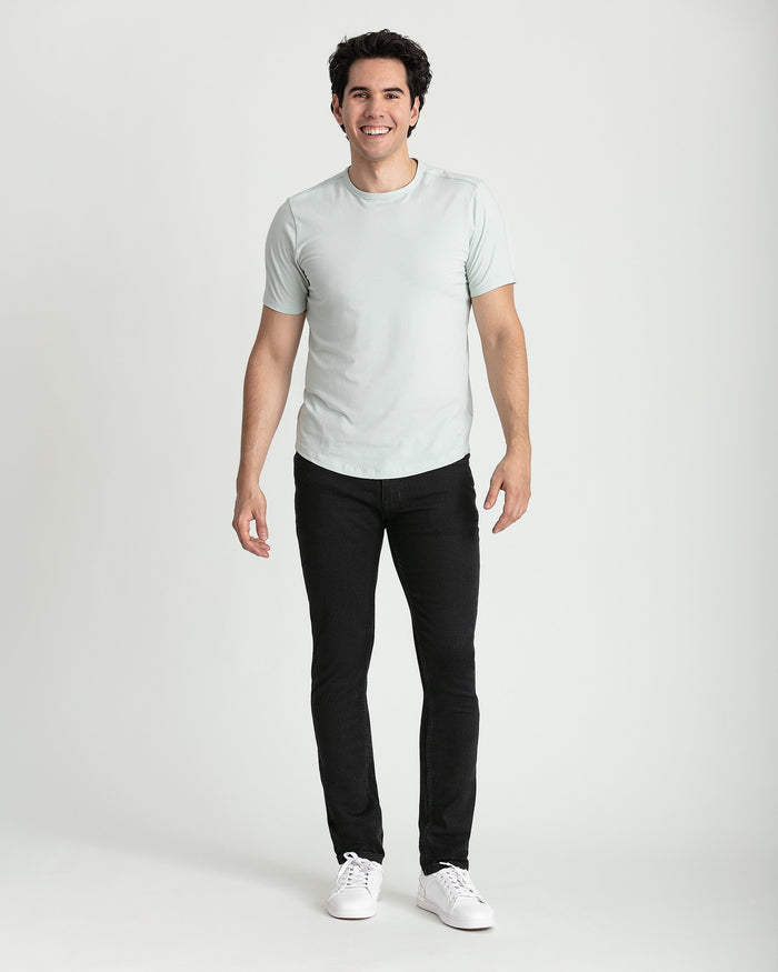 Man wearing light gray crew neck t-shirt and black skinny fit jeans with white sneakers.