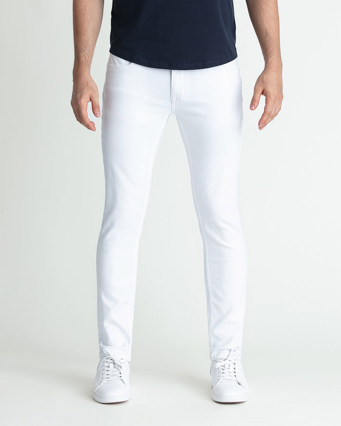 White skinny fit jeans on model wearing dark navy top and white sneakers.