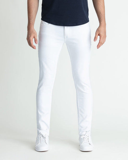 White skinny fit jeans on model wearing dark navy top and white sneakers.