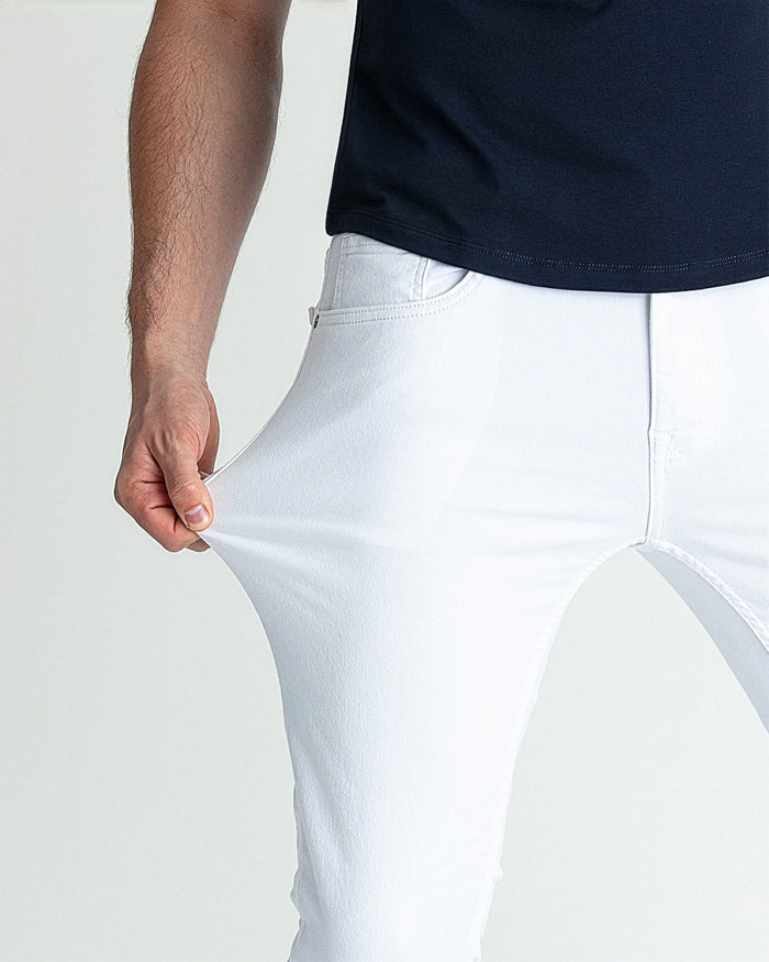 White skinny fit jeans on male model wearing navy shirt, showing fit at waist and thigh.