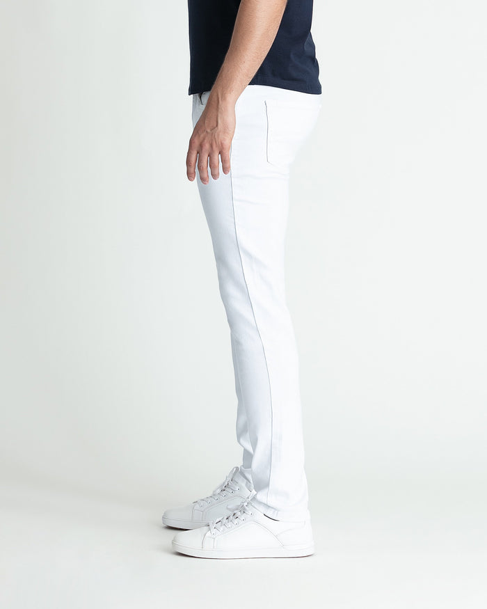 White skinny fit jeans with front pocket detail on male model wearing navy shirt and white sneakers.