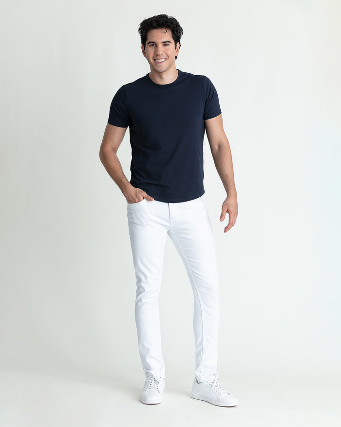Man wearing white skinny fit jeans with navy short-sleeve t-shirt and white sneakers.
