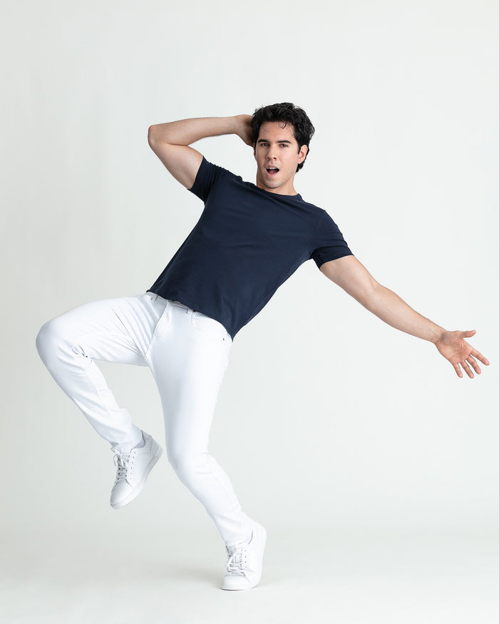 Man wearing white skinny fit jeans with navy t-shirt and white sneakers.