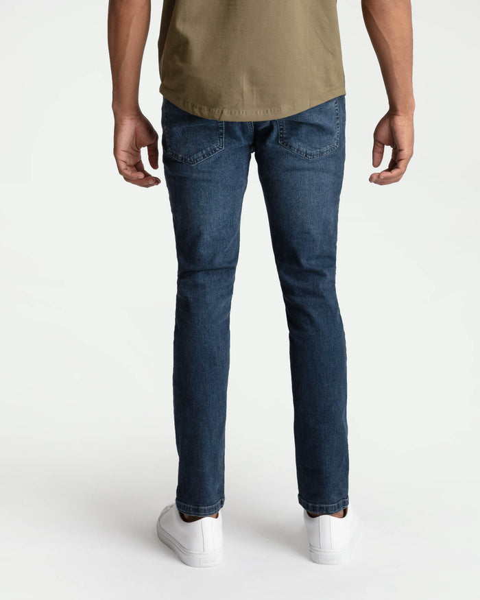 Man wearing midnight blue skinny fit jeans with tan t-shirt and white sneakers.
