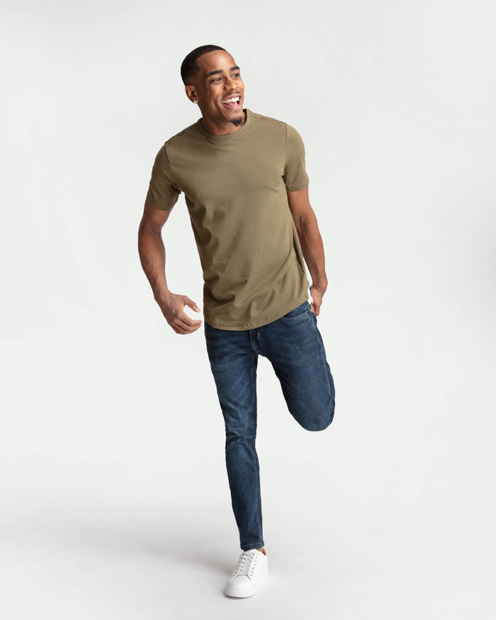 Man wearing tan short-sleeve t-shirt and dark blue skinny fit jeans with white sneakers.