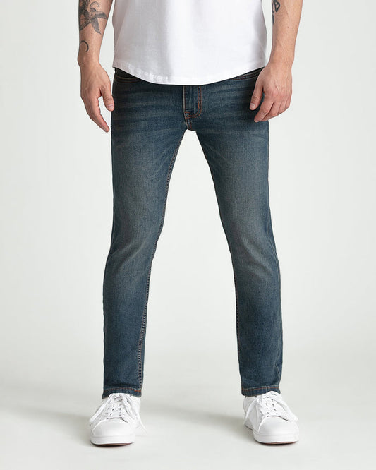 Dark tinted skinny fit jeans with orange stitching, worn with white t-shirt and white sneakers.
