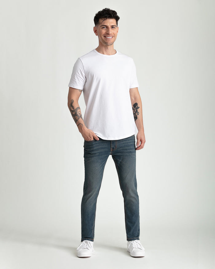 Man wearing white short-sleeve t-shirt and dark tinted skinny fit jeans with white sneakers.