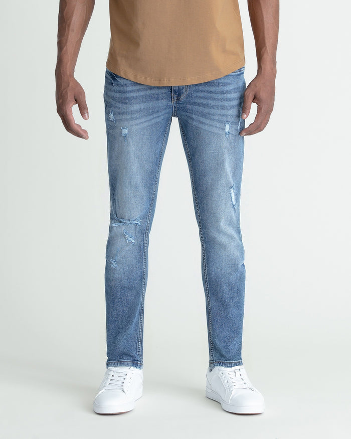 Men's skinny fit medium blue jeans with ripped detailing at thighs and knees.